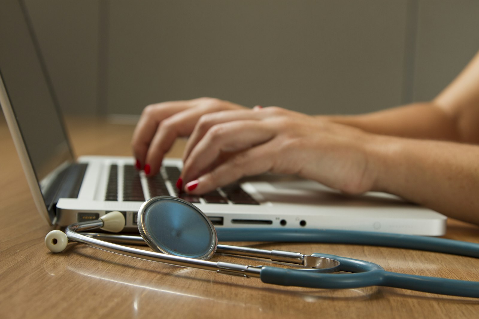 A healthcare worker entering records on a laptop